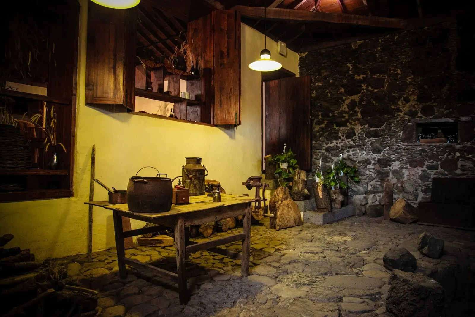 Hotel La Casona del Patio: A rustic kitchen with stone walls, wooden furniture, and various cooking utensils