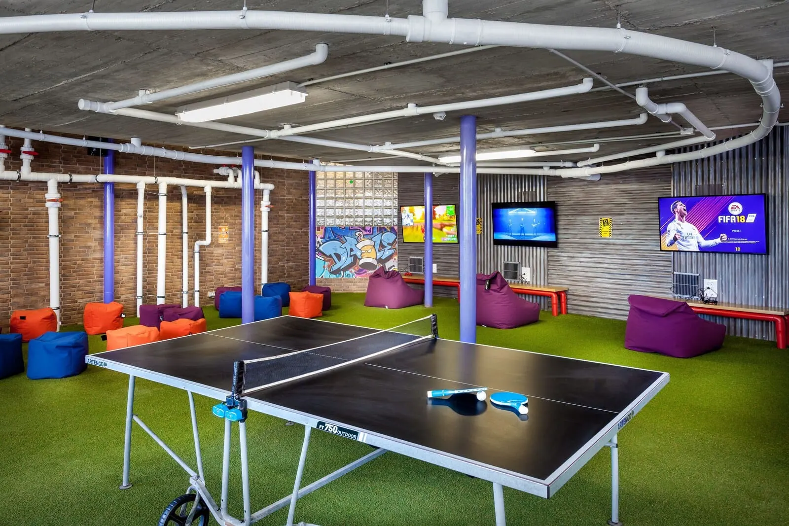 Playaolid Suites & Apartments: A ping pong table in a room with green artificial turf, colorful bean bags