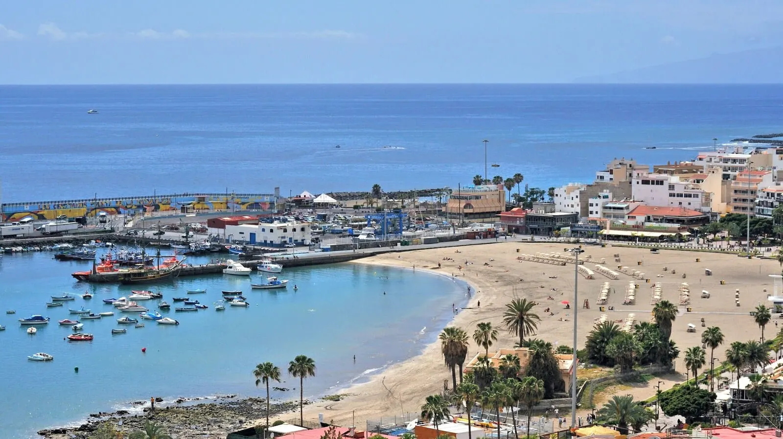 Sol Arona Tenerife: A coastal town with a beach, boats, and buildings