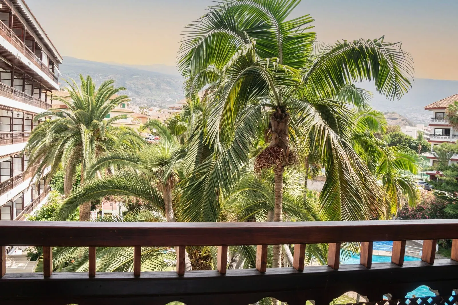 Coral Teide Mar: A balcony with a view of a coastal town, palm trees, and a clear sky