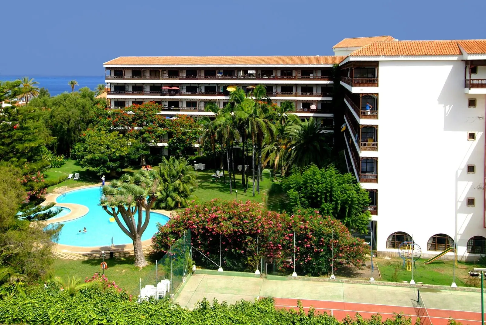 Coral Teide Mar: A hotel with a swimming pool, lush greenery, and a view of the sea