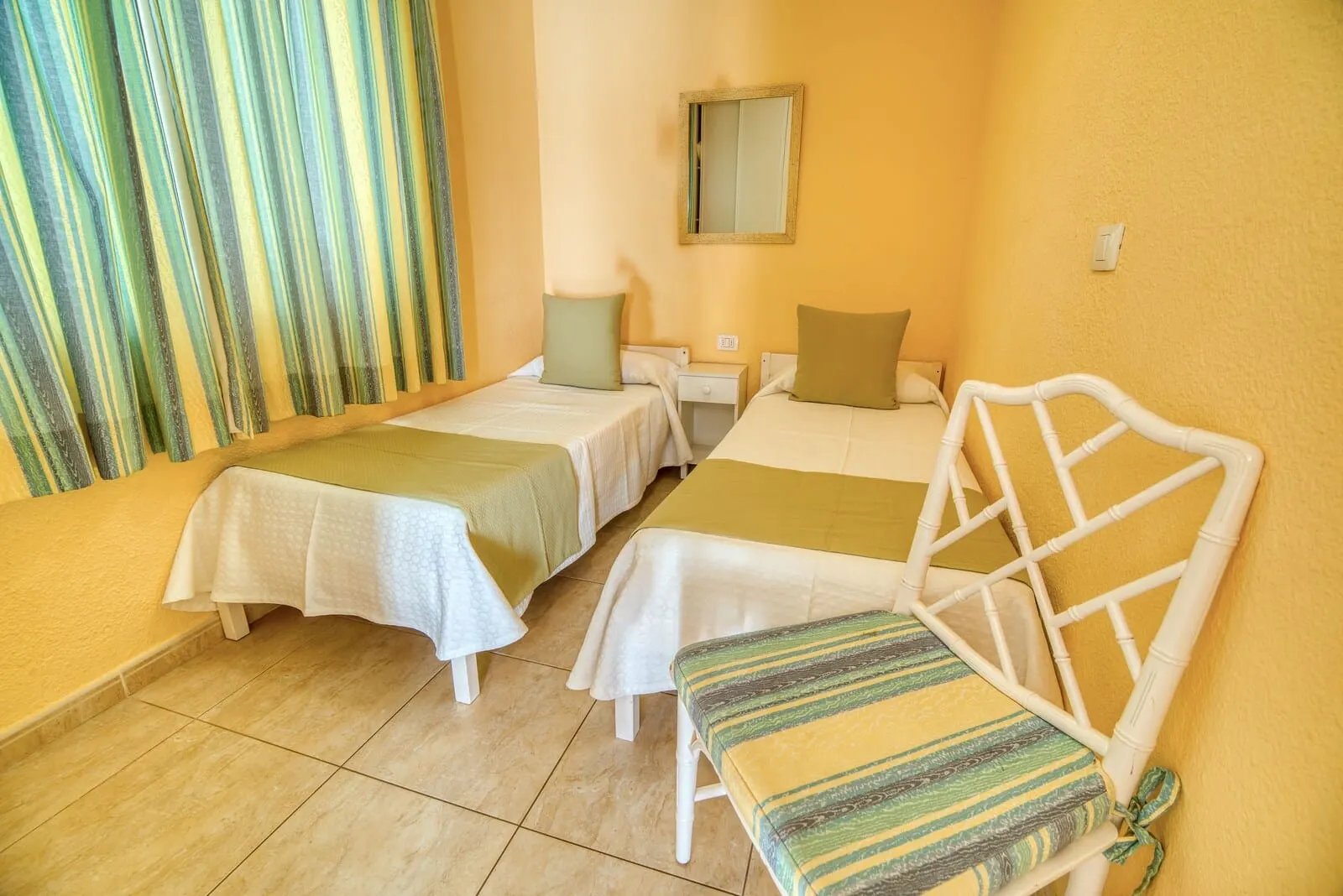 Ona Sueño Azul: A room with two single beds, a small table, a chair, and a mirror on the wall