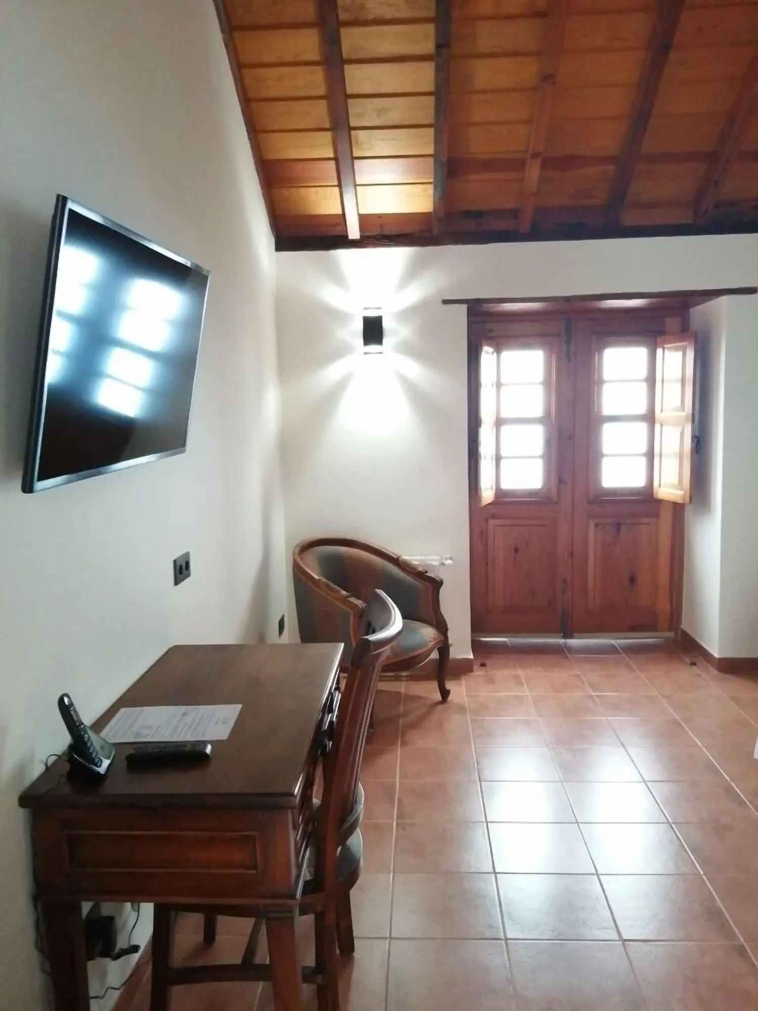 Hotel Rural Casablanca: A room with a wooden ceiling, a TV mounted on the wall, a dining table with chairs