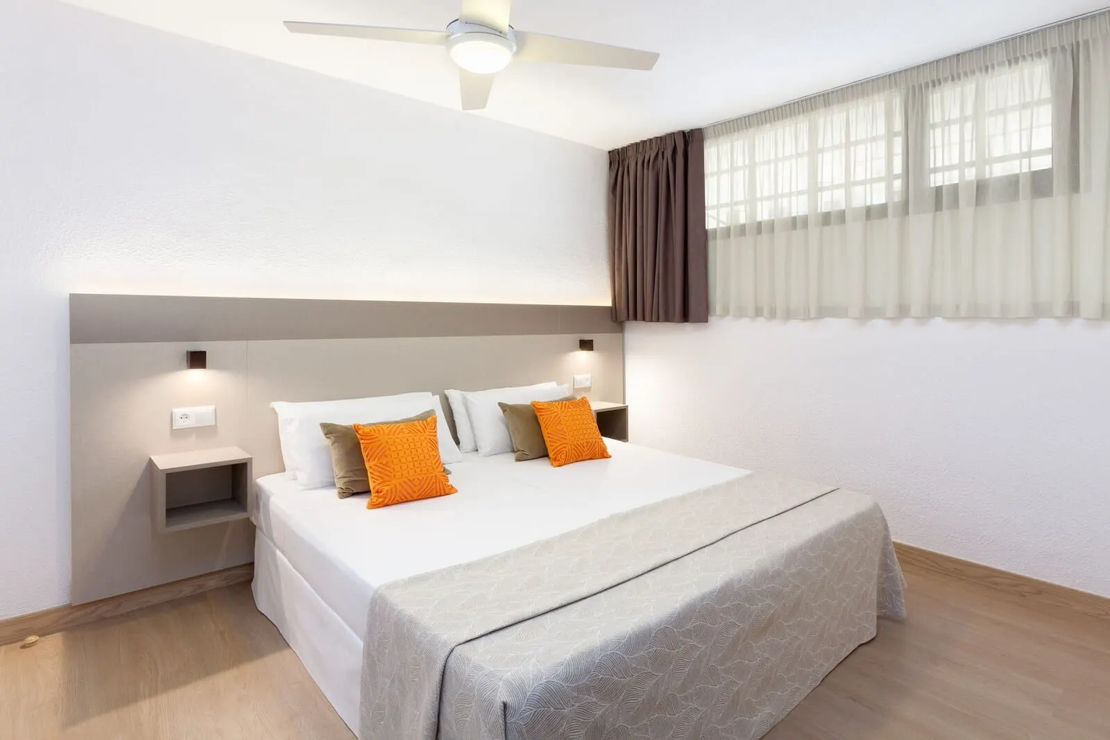 Apartamentos Aguamar: A modern hotel room with a large bed, two bedside tables, a ceiling fan