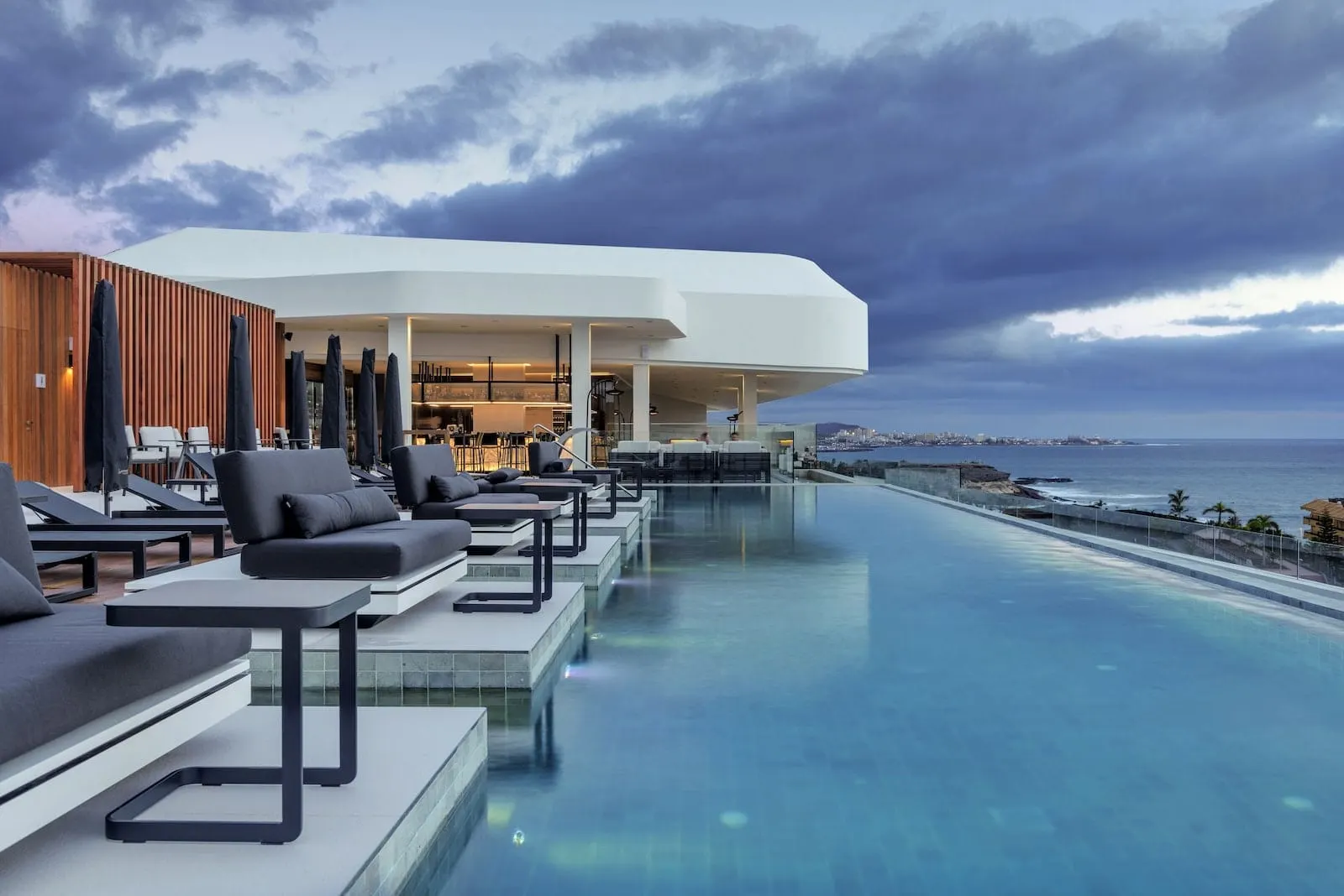 Royal Hideaway Corales Beach: A modern infinity pool with lounge chairs and a covered seating area overlooking