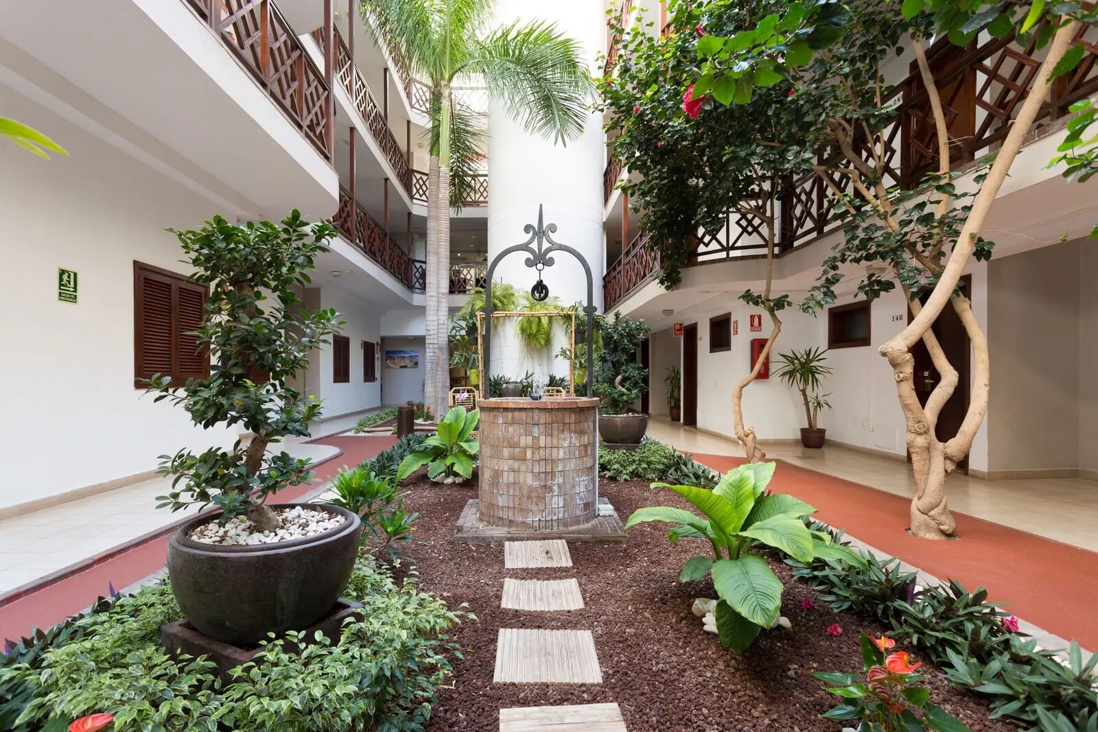 Globales Tamaimo Tropical: A courtyard with a central fountain, surrounded by potted plants and a stone pathway