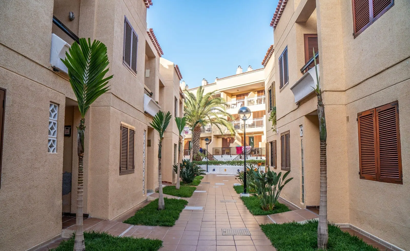 Coral Compostela Beach: A courtyard with a central pathway flanked by buildings with balconies and shutters