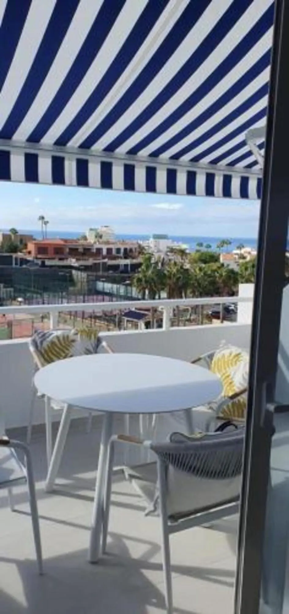 Malibu Park: A balcony with a striped awning, white round table, and wicker chairs