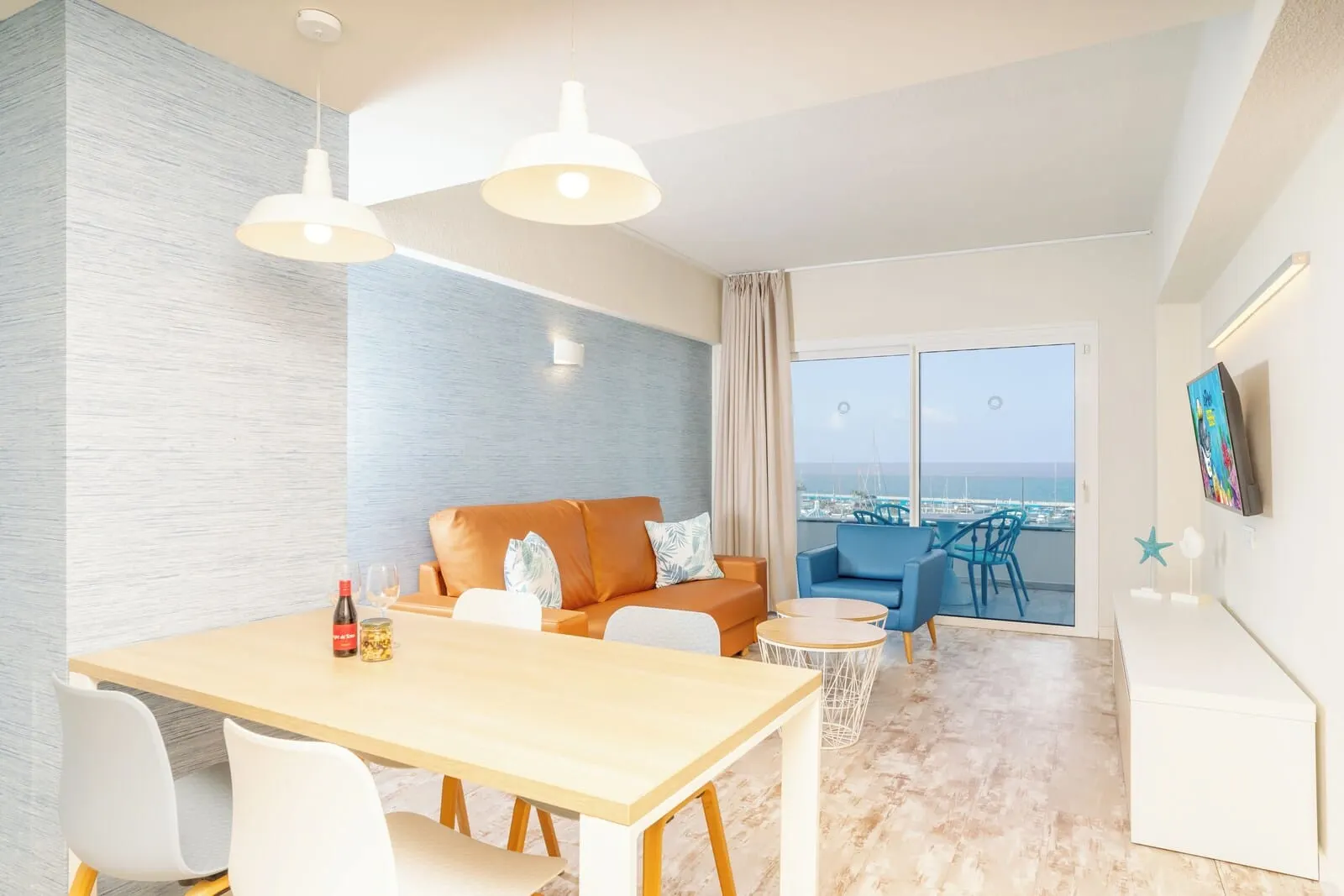 HOVIMA La Pinta Beachfront Family Hotel: A modern living room with a wooden dining table, white chairs