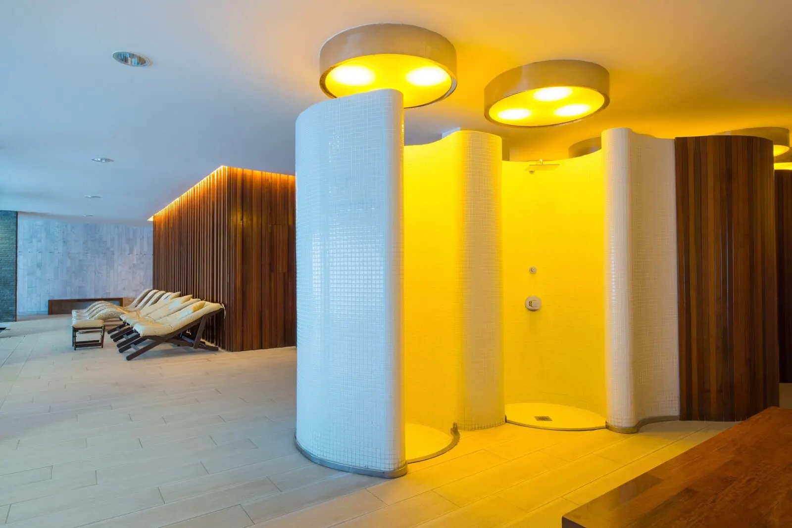 Iberostar Selection Anthelia: A modern spa area with a wooden bench, a large white pillar, and a yellow-lit wall