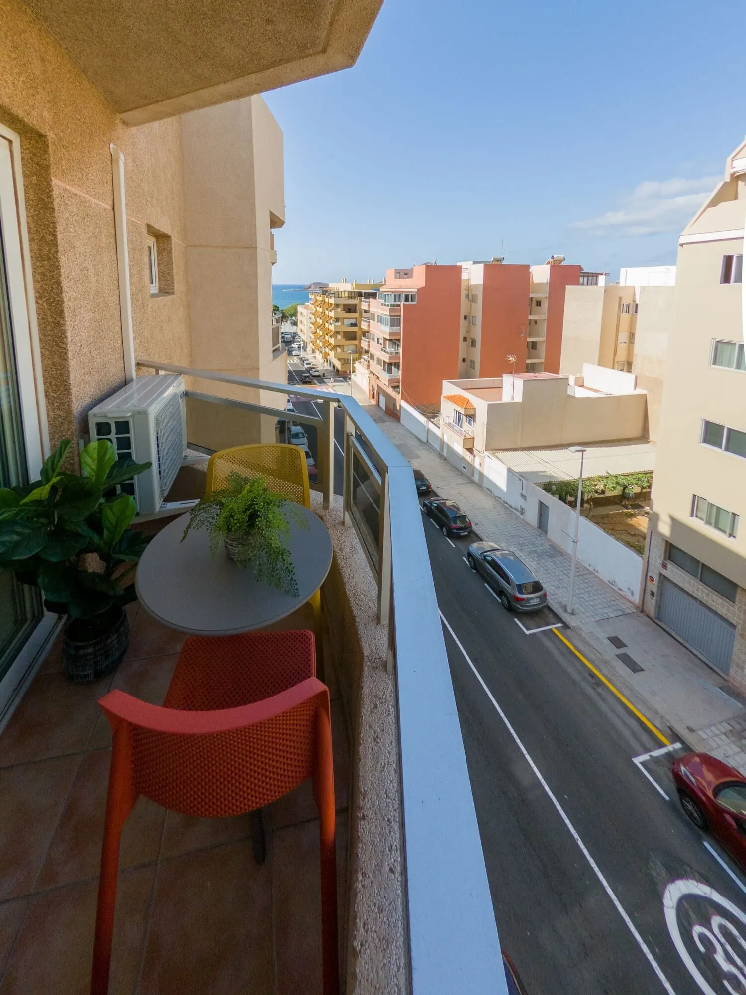 Hotel Ventus: A balcony with a table and chairs, overlooking a street with parked cars and buildings