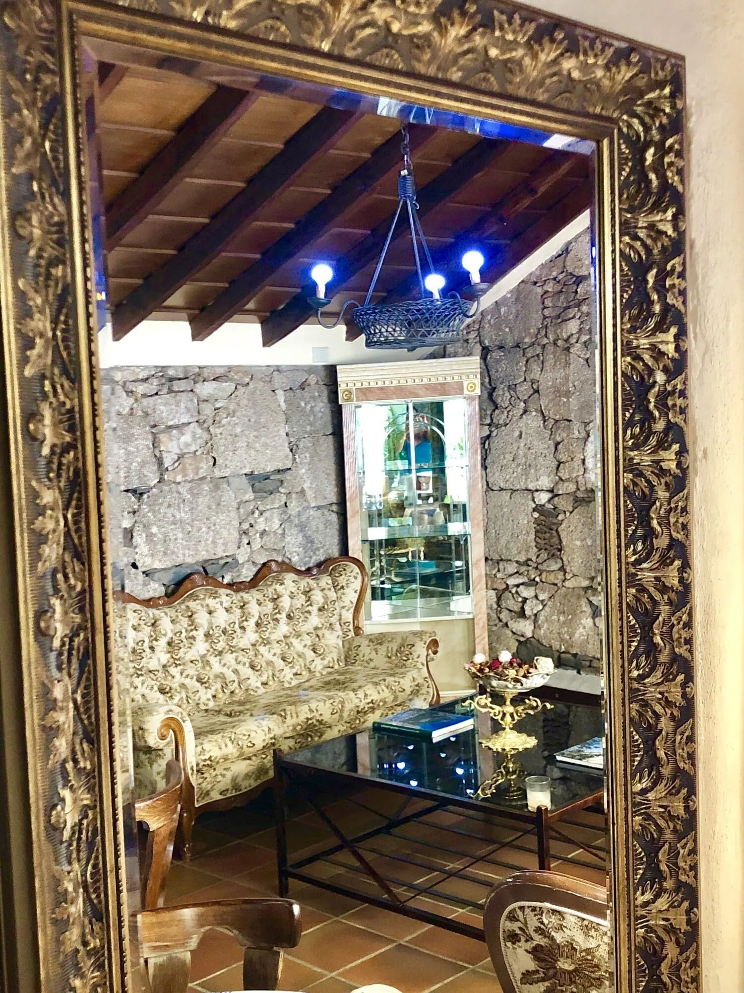 Hotel Rural Vilaflor: A room with a stone wall, a patterned sofa, a wooden chair, a glass coffee table
