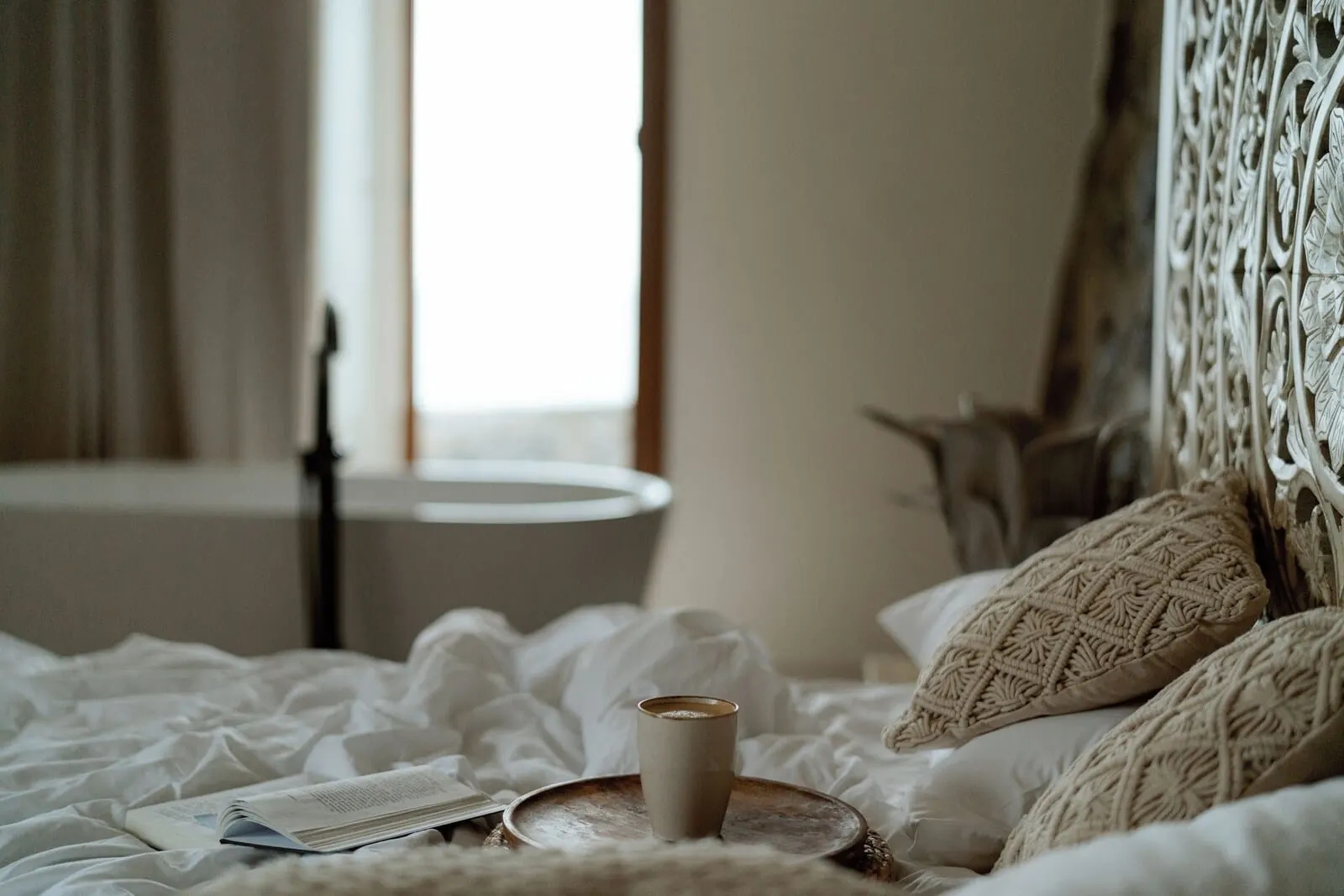 Costa Mágica Boutique Hotel: A bed with a cup and a book, a bedside table, and a window with curtains