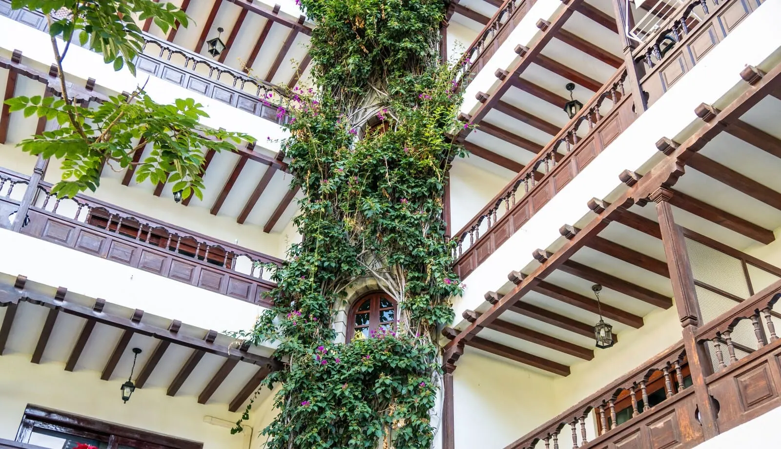 Coral Teide Mar: A multi-story building with wooden balconies and a central column covered in greenery