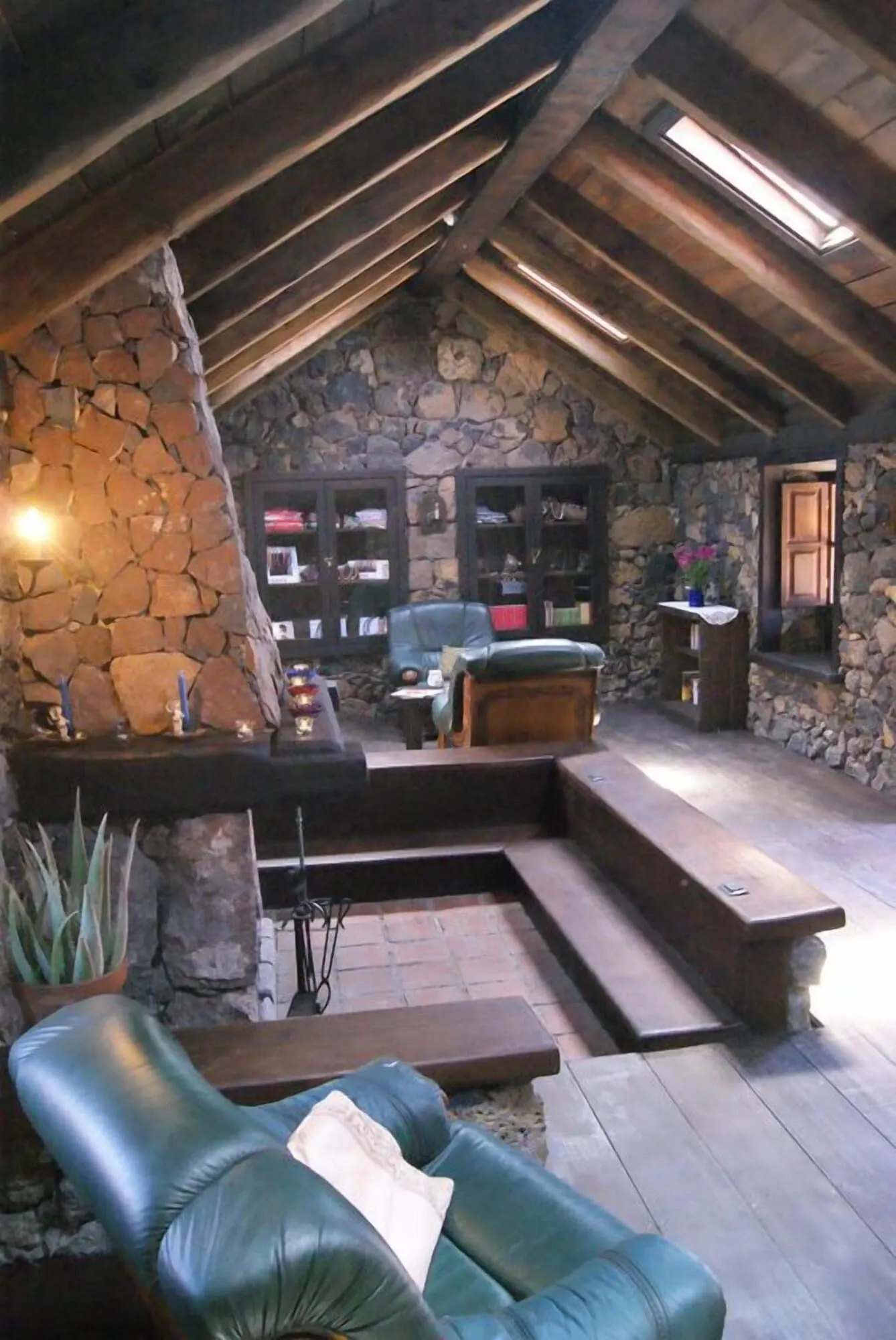 Hotel Rural Caserío Los Partidos: A cozy loft-style living area with a stone wall, leather furniture