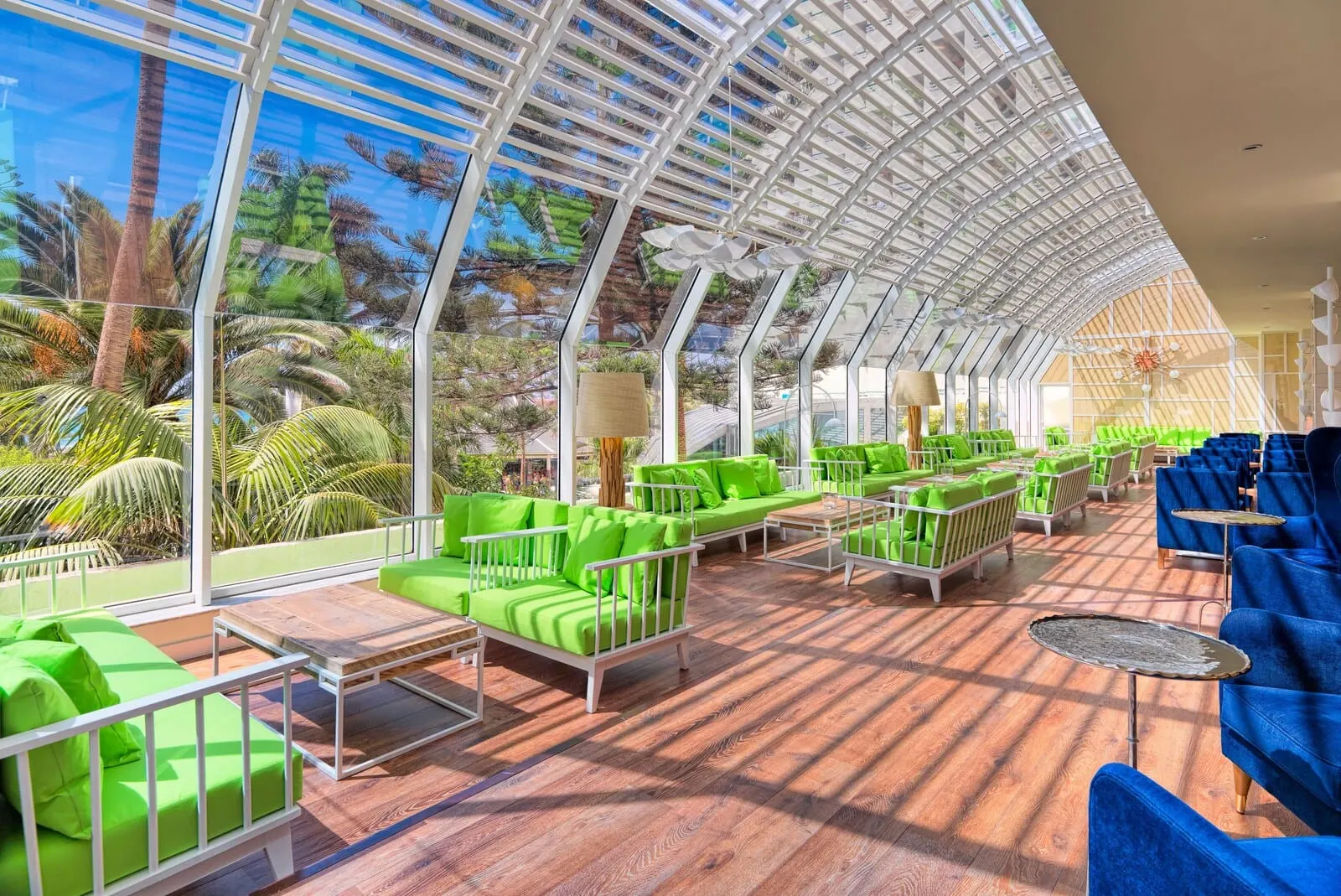 H10 Las Palmeras: A spacious indoor area with a glass ceiling, green and blue seating