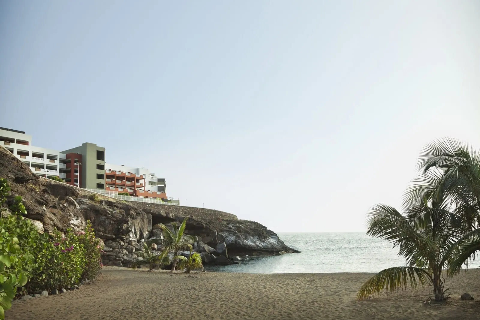 Roca Nivaria Gran Hotel: A beach with a rocky cliff, palm trees