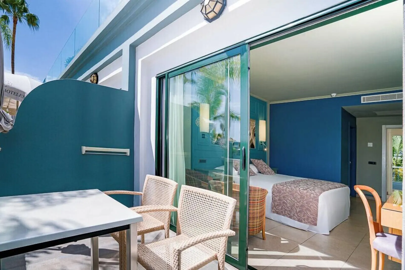Hotel Colón Guanahaní: A room with a bed, a glass door leading to a balcony, wicker chairs, and a table