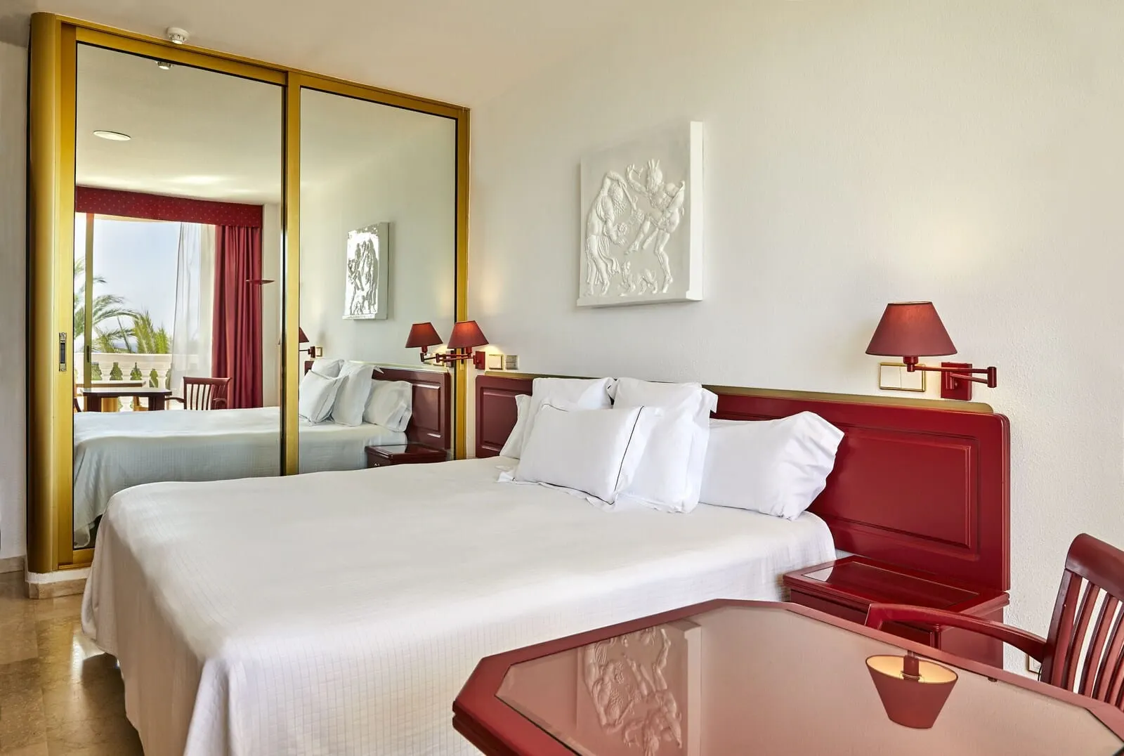 Cleopatra Palace: A hotel room with a large bed, a bedside table, a mirror, and a painting on the wall
