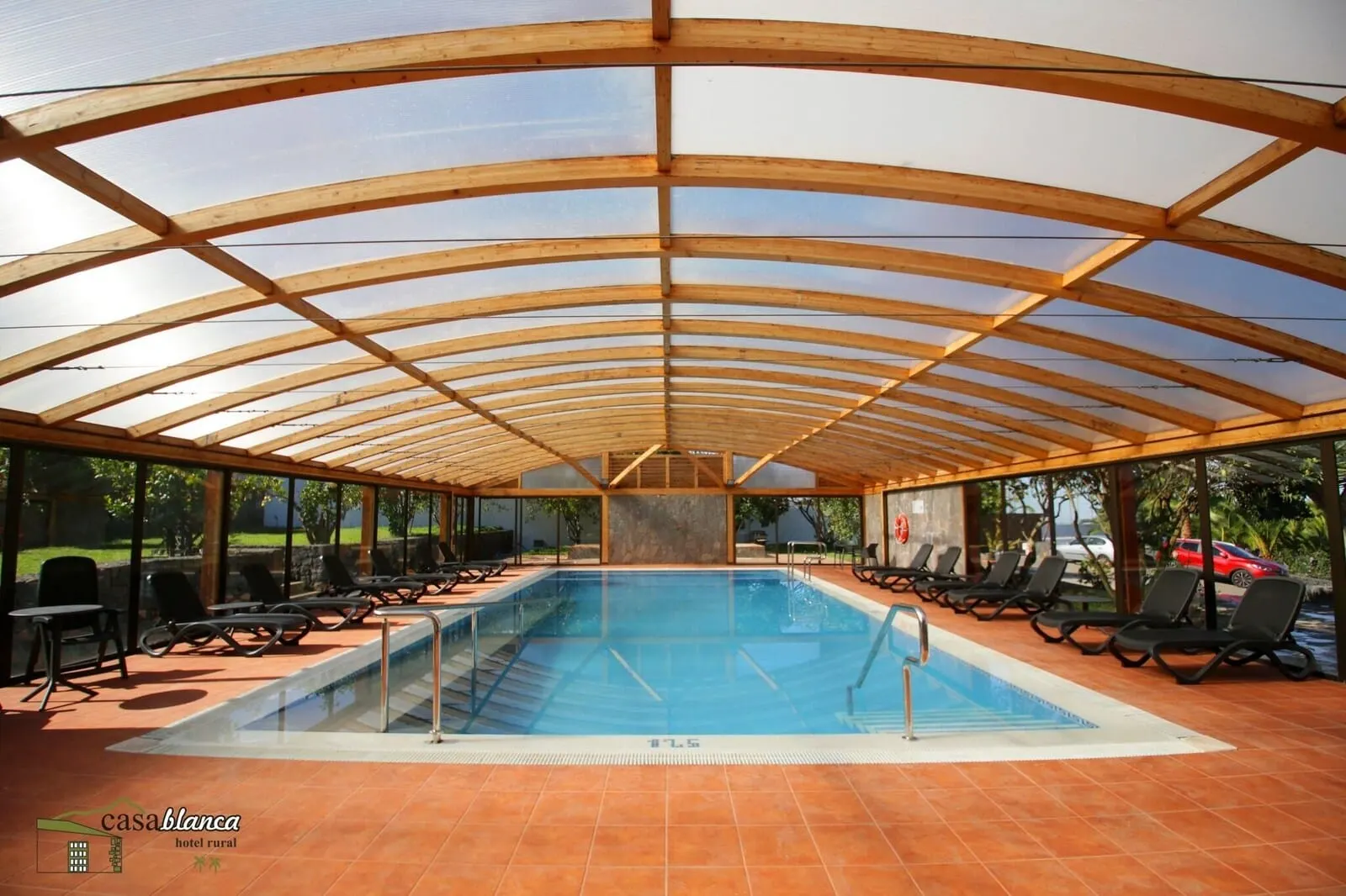 Hotel Rural Casablanca: An indoor swimming pool with a wooden roof and tiled floor, surrounded by lounge chairs