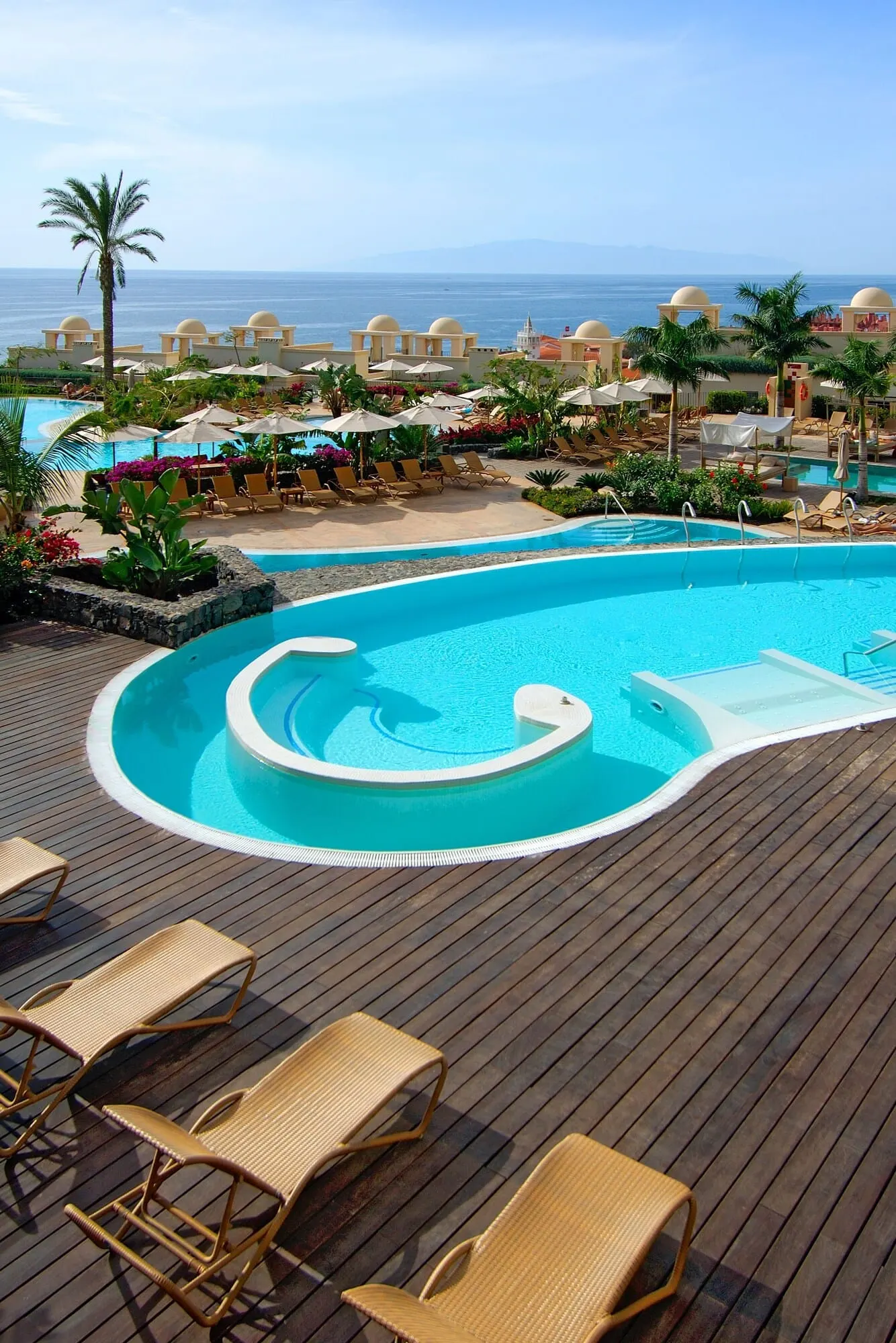 Vincci Selección La Plantación del Sur: A pool area with lounge chairs and umbrellas, a wooden deck, and a view of the ocean