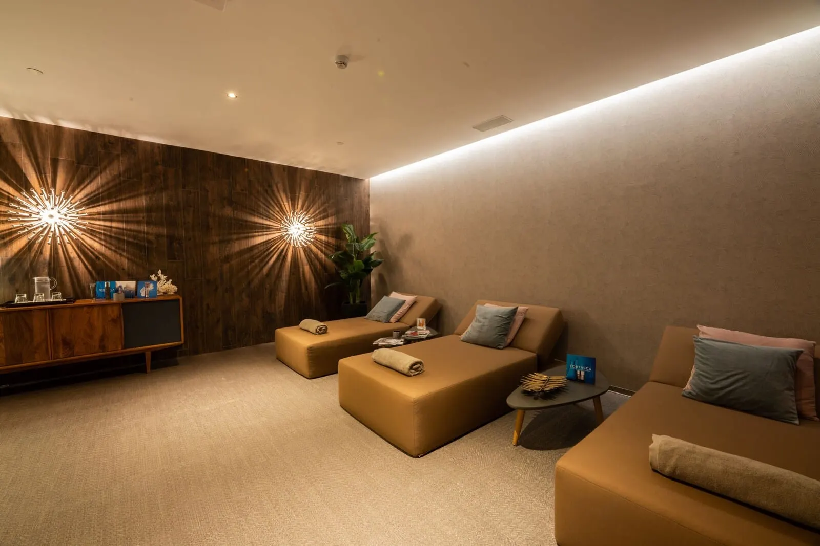 Sir Anthony: A modern spa room with two sofas, a wooden cabinet, and a small table with amenities