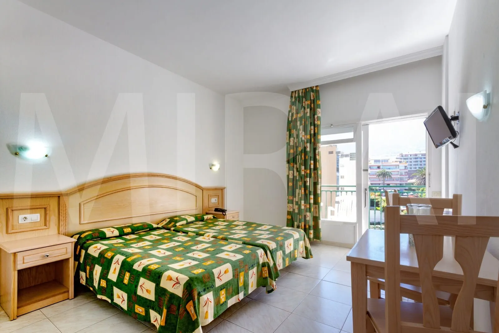 Apartamentos La Carabela: A hotel room with a double bed, a wooden desk, a chair, a TV mounted on the wall