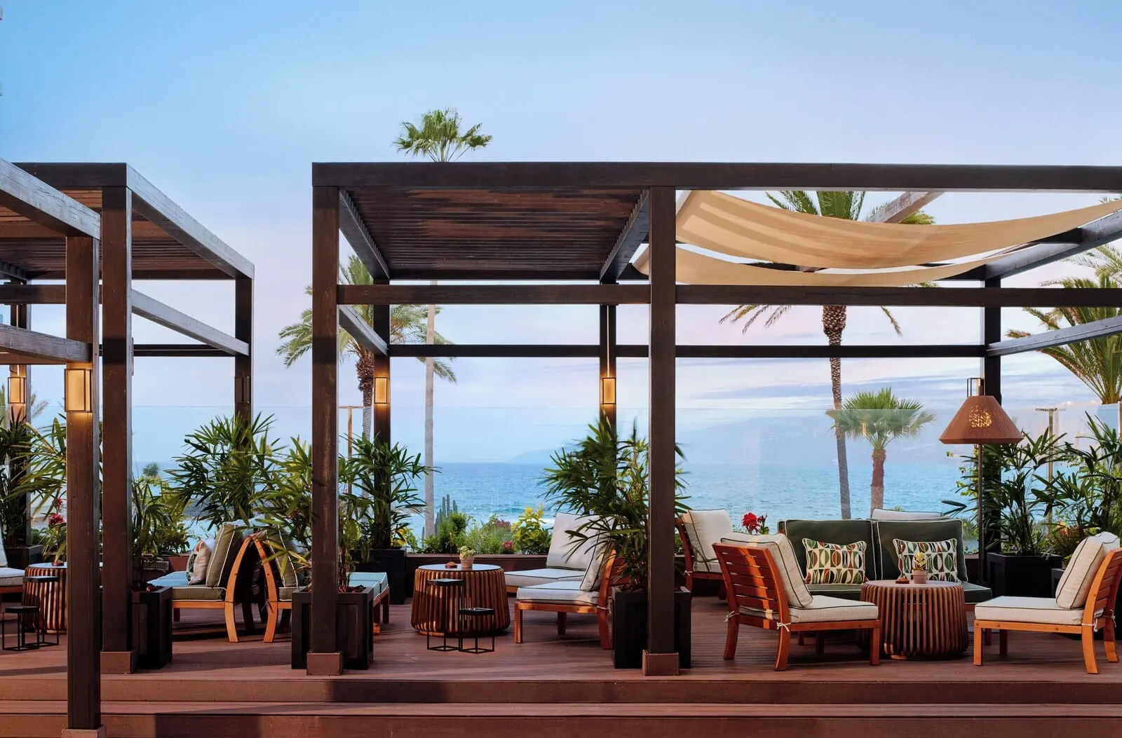 Meliá Costa Atlantis Tenerife: An outdoor seating area with wooden furniture, a canopy, and a view of the ocean