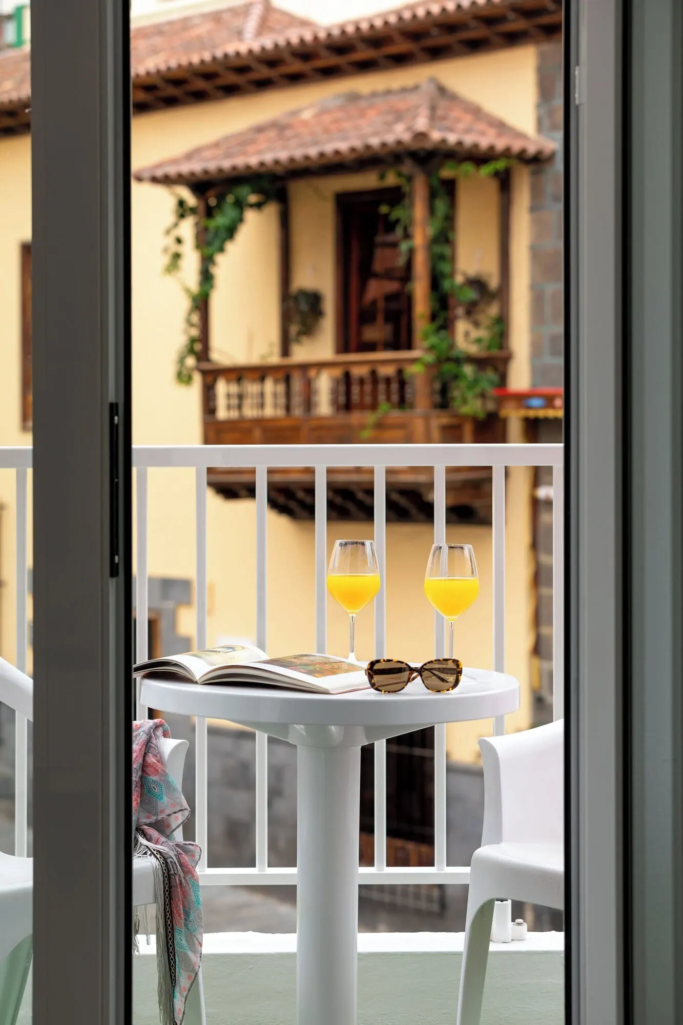 Hotel Boutique HC Maga: A balcony with a table, two glasses of orange juice, and a pair of sunglasses