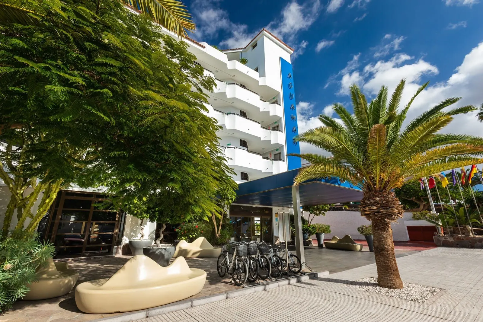 Apartamentos Aguamar: A hotel with a white facade, multiple balconies, and a covered entrance