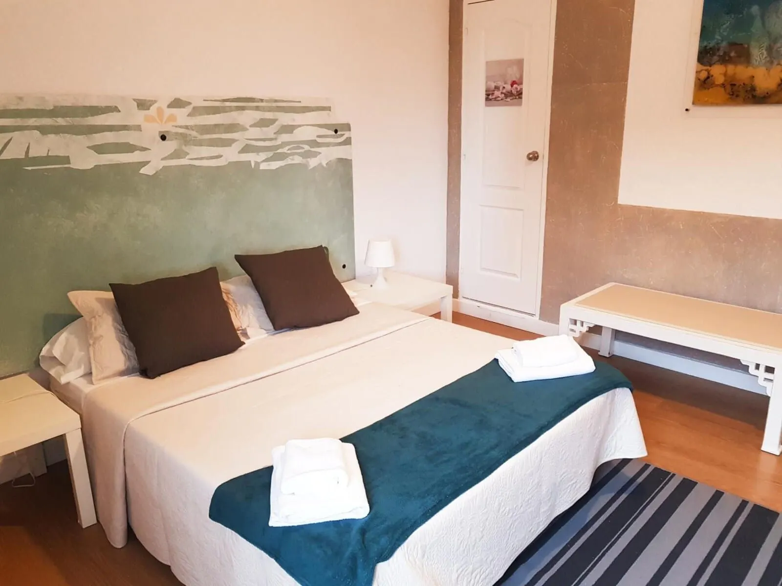 Nuevo Hotel Horizonte: A neatly made bed with white and brown bedding, a green throw blanket