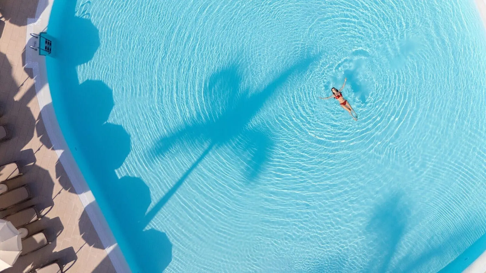 AluaSoul Costa Adeje: An aerial view of a swimming pool with clear water, a person swimming