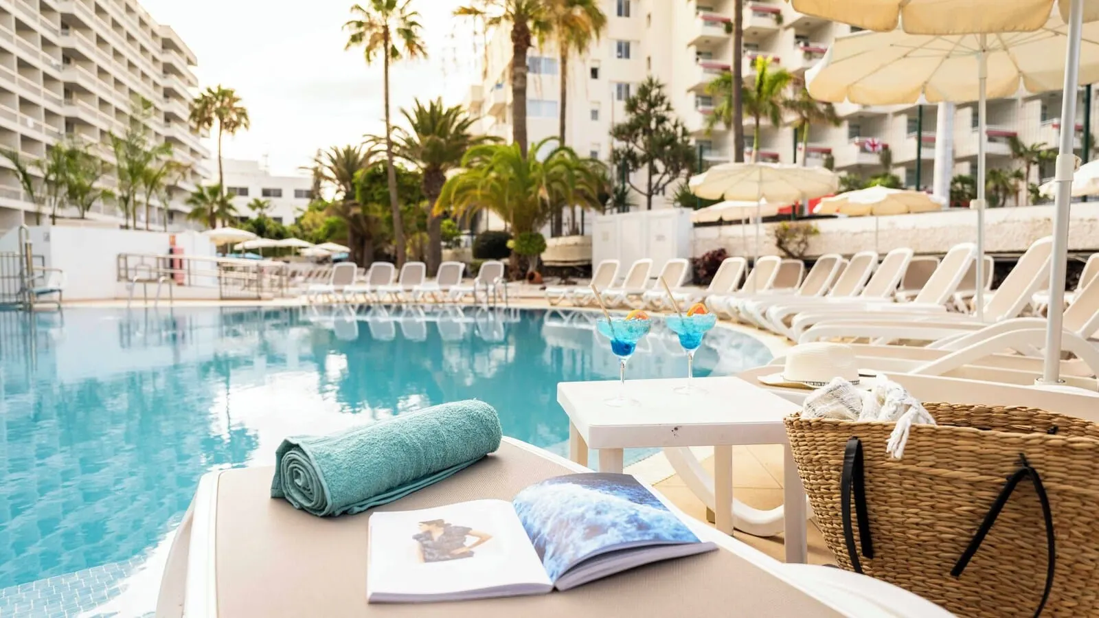 Ona Palm Beach: A poolside area with lounge chairs, a towel, a drink, and a book