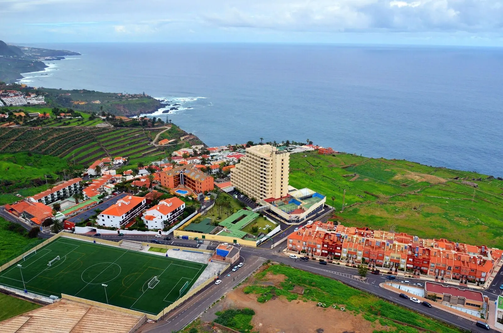 Hotel Panorámica Garden: An aerial view of a coastal town with a large hotel complex, a sports field