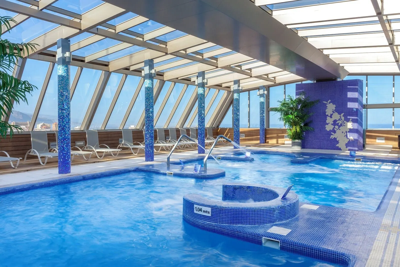 Meliá Costa Atlantis Tenerife: A swimming pool with a glass ceiling, lounge chairs, and a hot tub