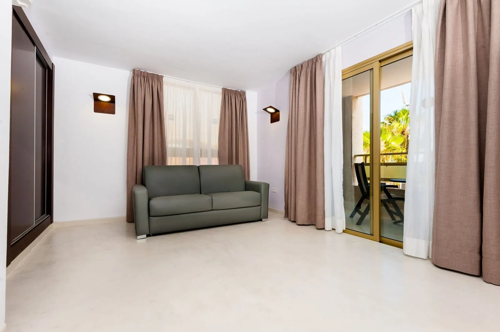 KN Aparthotel Columbus: A room with a sofa, curtains, and a sliding glass door leading to an outdoor area