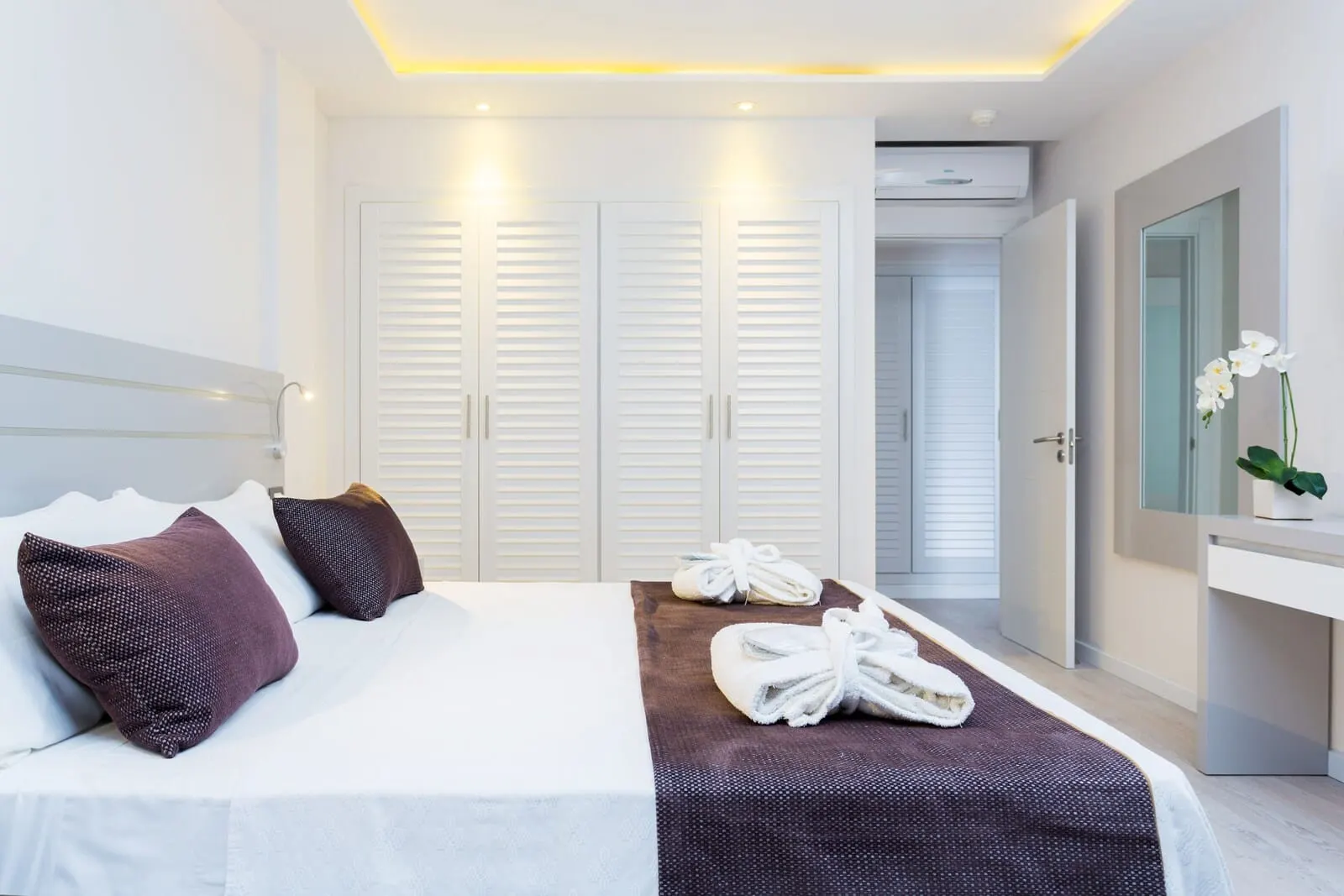 Royal Sun Resort: A hotel room with a neatly made bed, white curtains, a mirror, and a plant