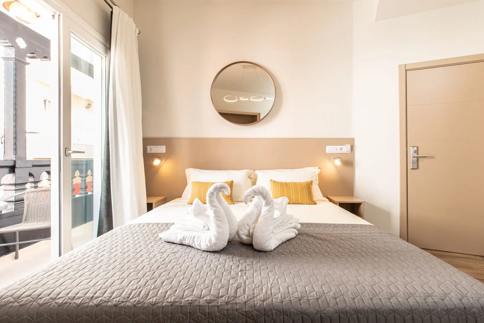 Suncanarias Hotel Adeje Plaza: A hotel room with a bed, a round mirror on the wall, and a door