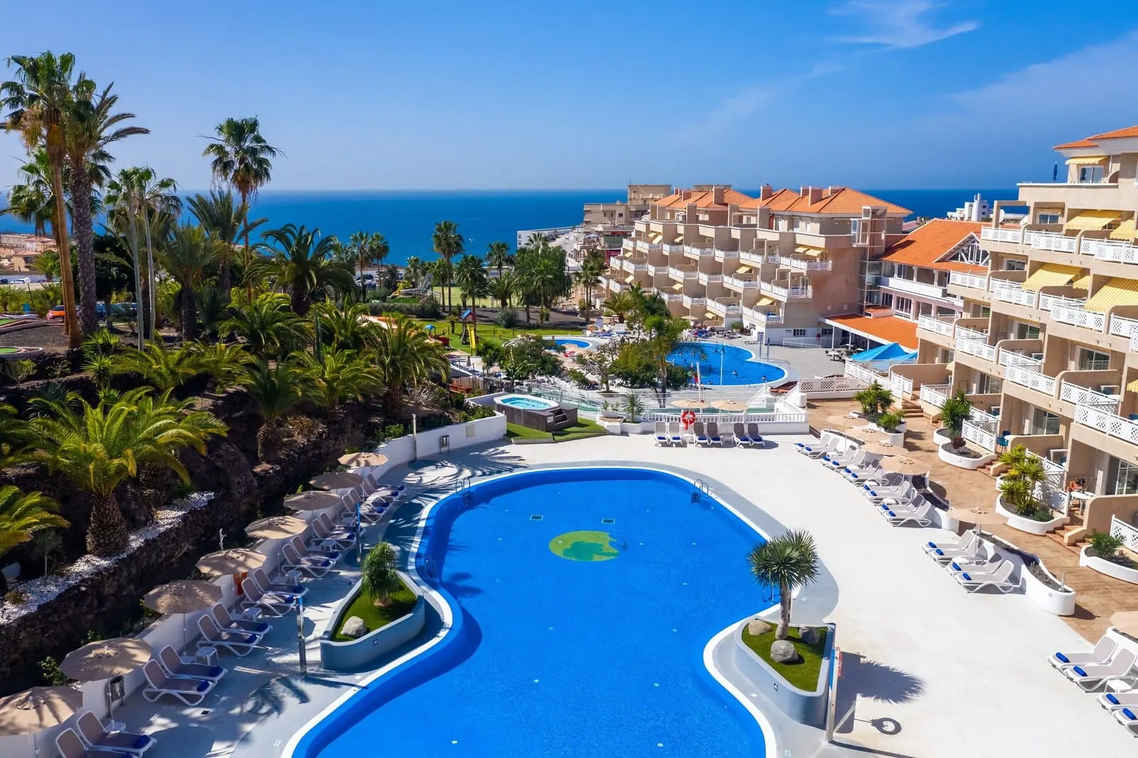 Hotel Tropical Park: A resort with a large pool, palm trees, and a view of the sea