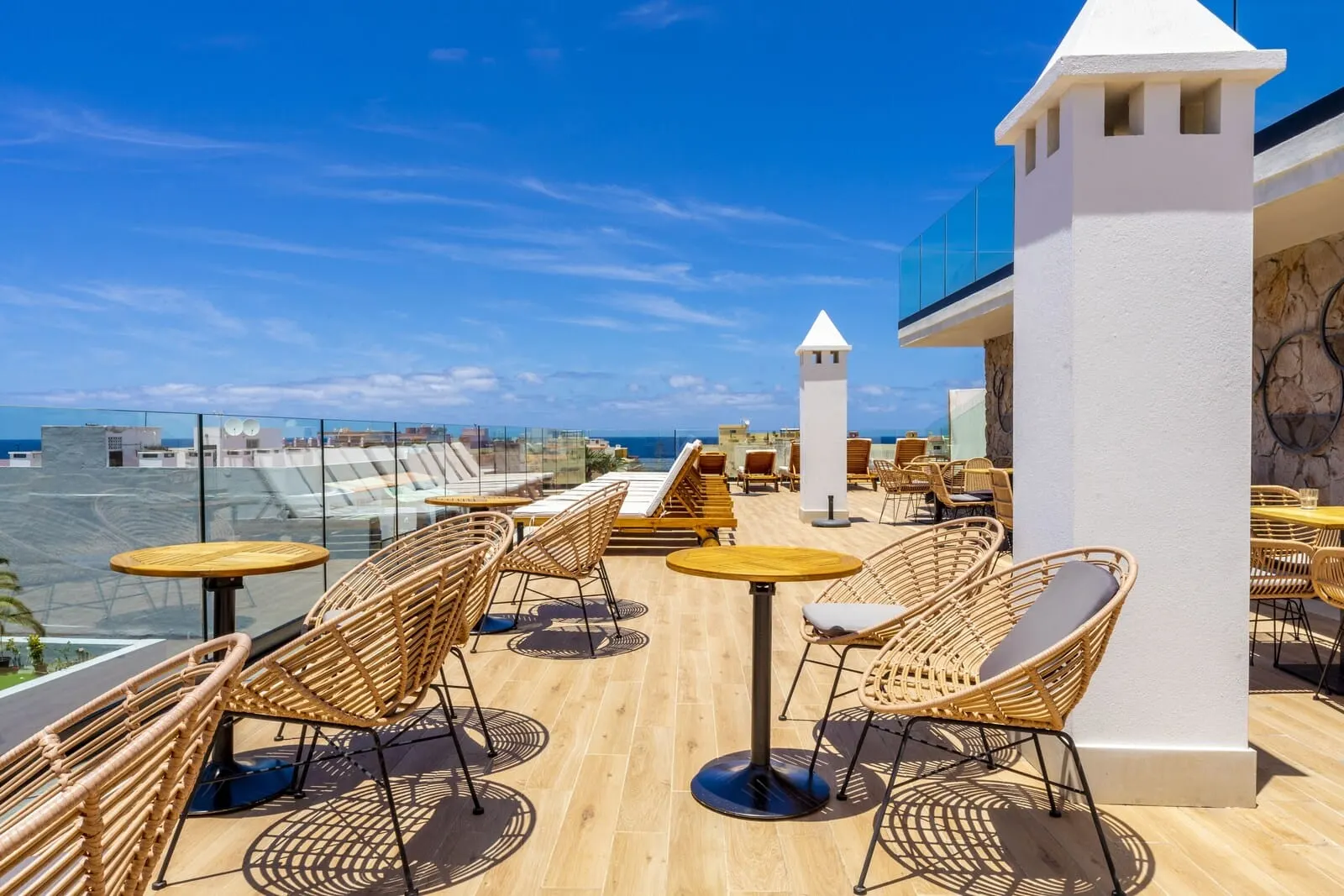 DWO Nopal: A rooftop terrace with wicker chairs and tables, overlooking a cityscape and the sea