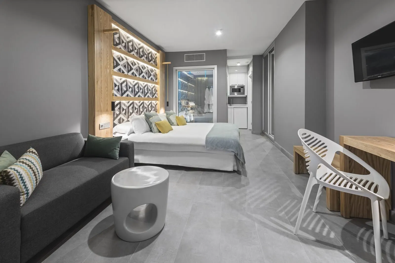 Atlantic Mirage Suites & Spa: A modern hotel room with a bed, a sofa, a dining area, and a TV