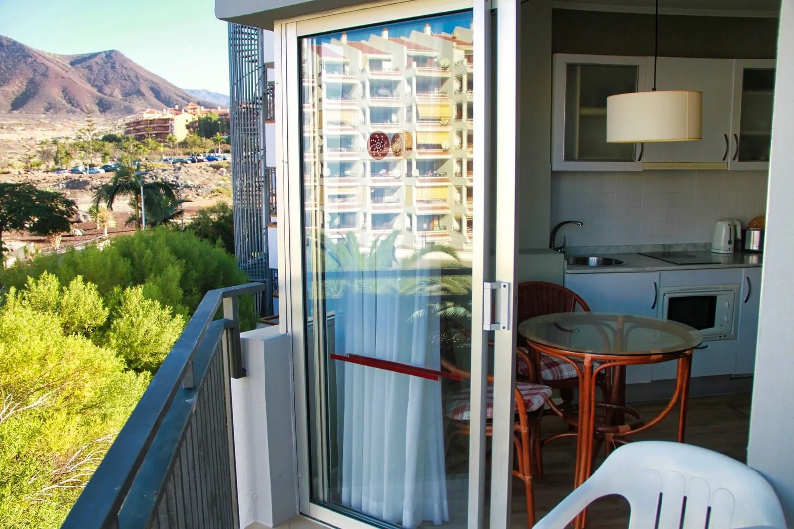 HG Tenerife Sur: A balcony with a glass door, a dining area with a table and chairs