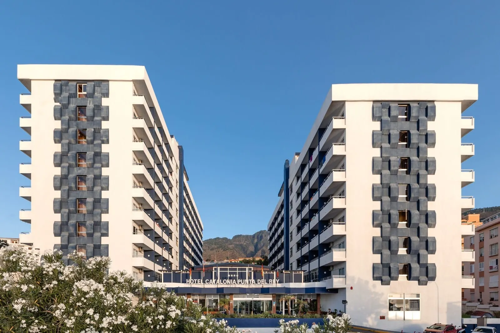 Catalonia Punta del Rey: A modern hotel with a symmetrical facade, multiple balconies, and a central entrance