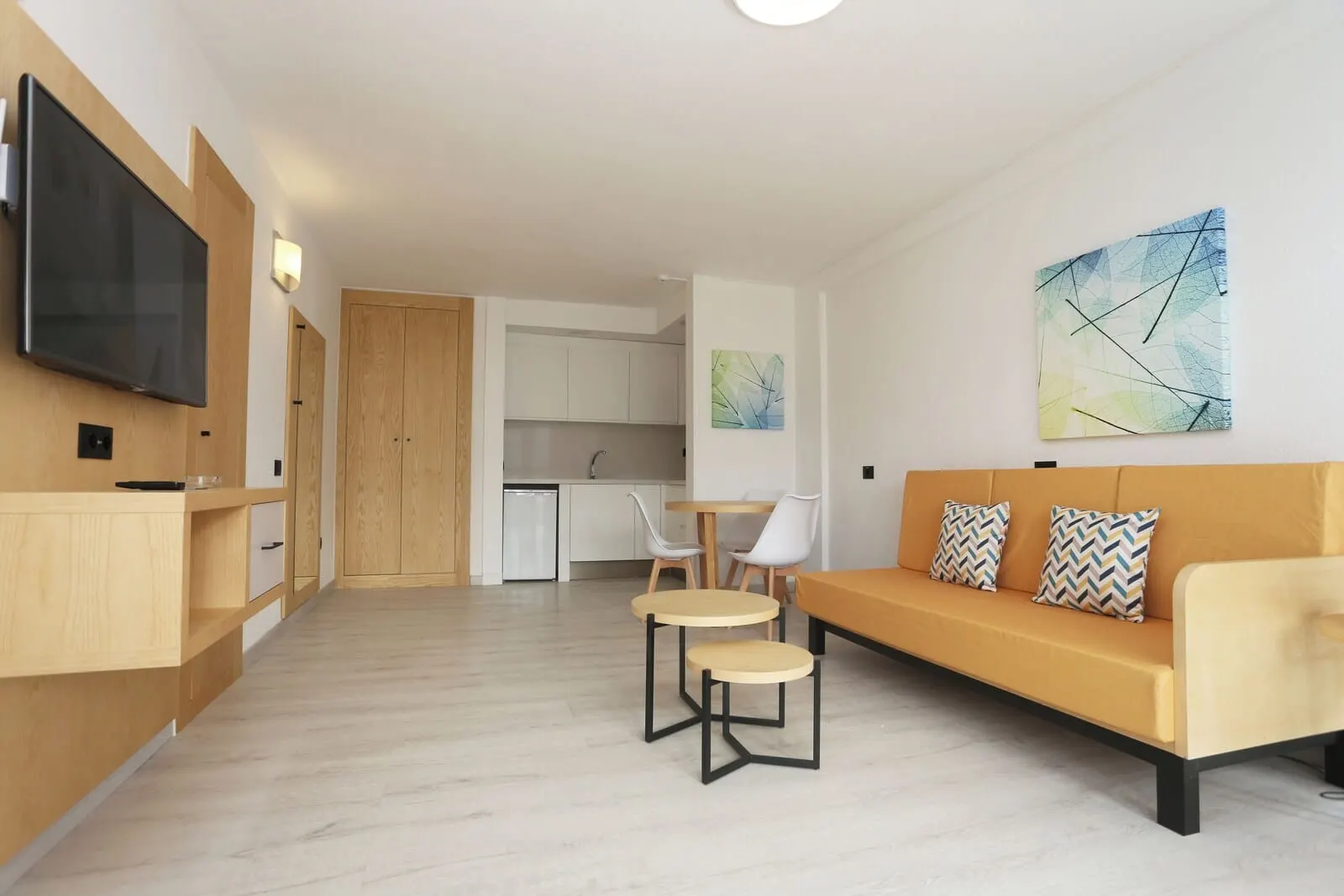 Hotel Andorra: A modern living room with a sofa, two small tables, and a TV mounted on the wall