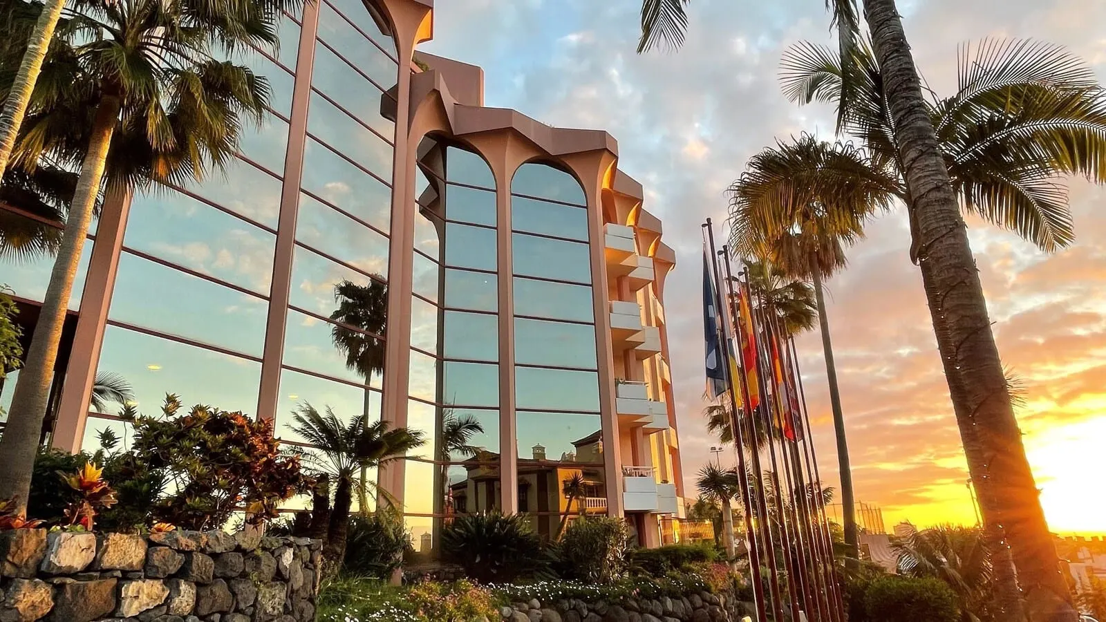 Hotel Puerto Palace: A modern hotel with a glass facade, a stone foundation