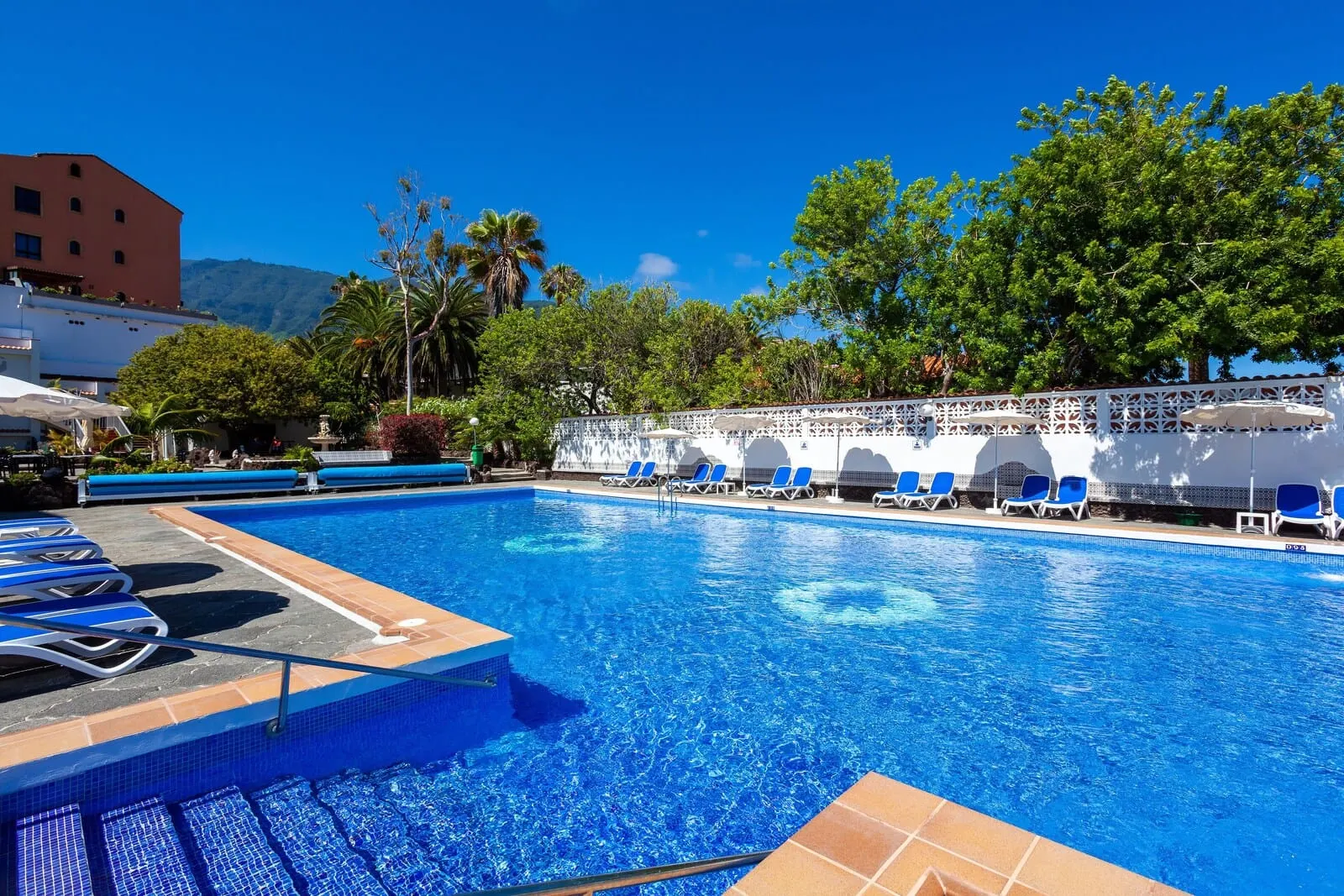 Hotel Panorámica Garden: A swimming pool with blue water, surrounded by lounge chairs and a white fence