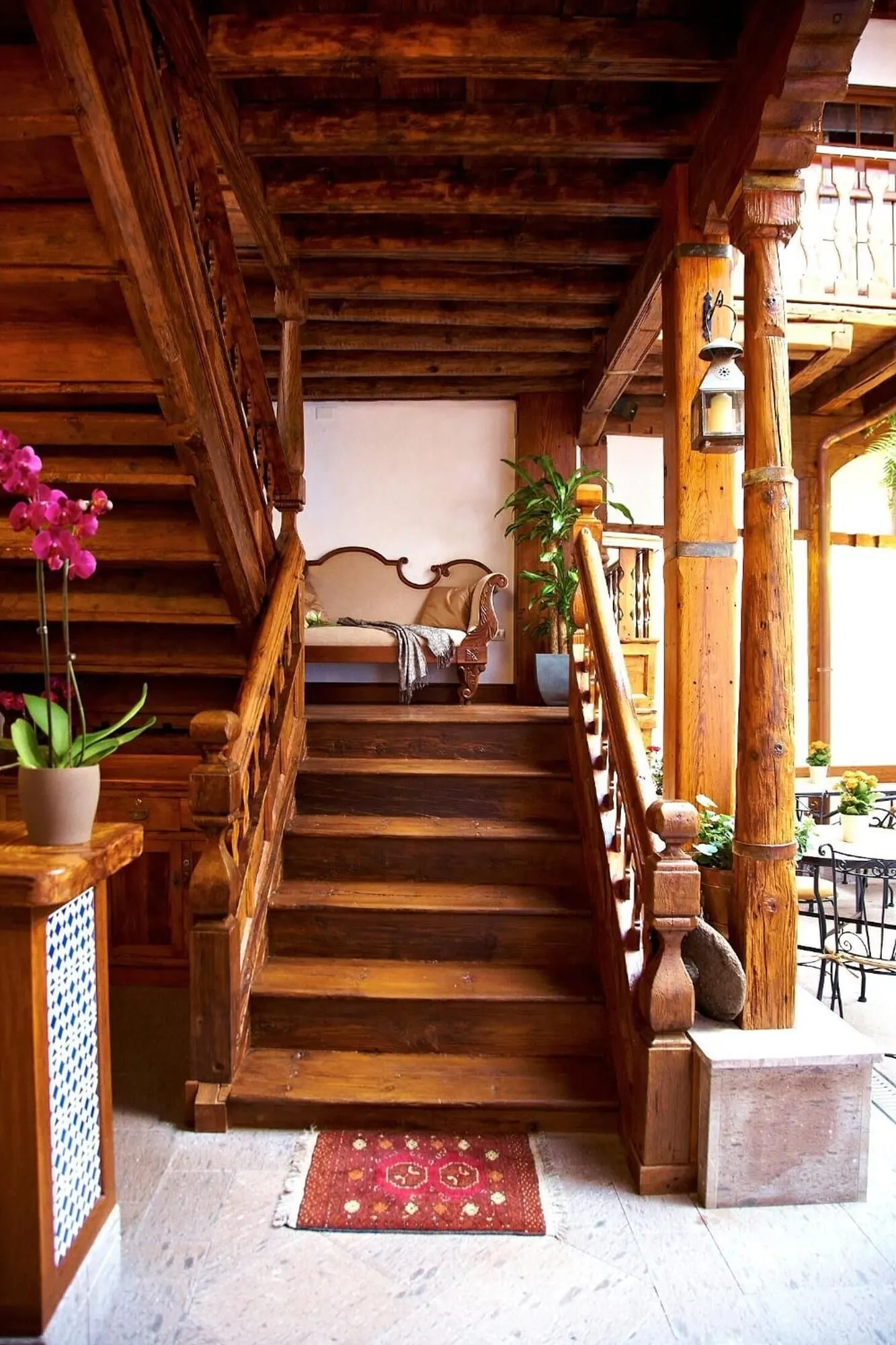 Hotel Emblemático San Agustín: A wooden staircase with a handrail, a potted plant, and a red rug on the floor