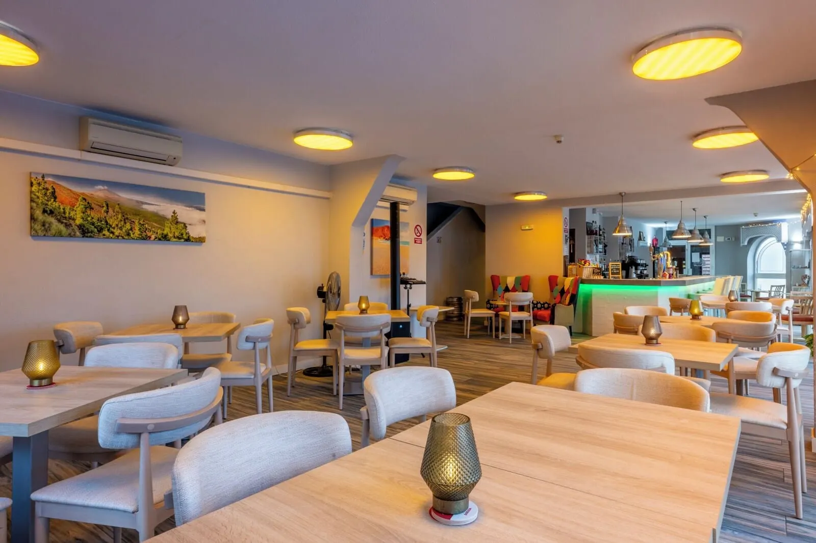 Ona Los Claveles: A modern restaurant interior with multiple dining tables and chairs, a bar area