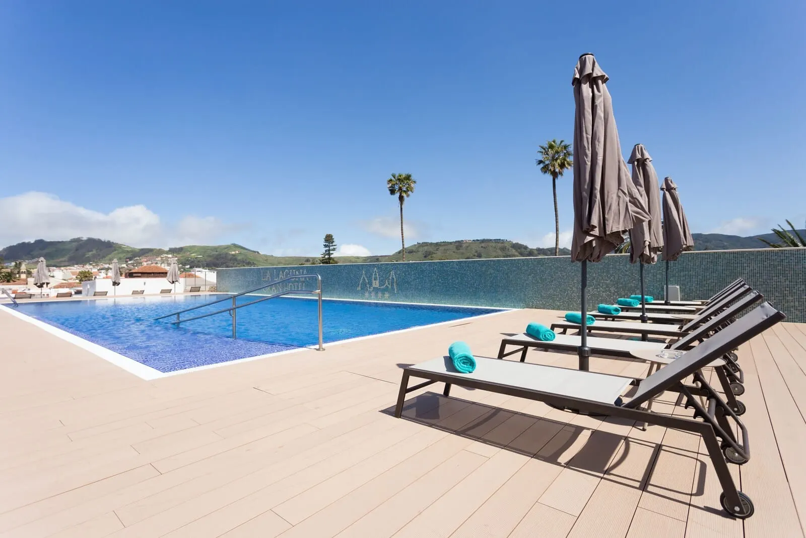 La Laguna Gran Hotel: A rooftop pool area with lounge chairs and umbrellas, a clear blue sky