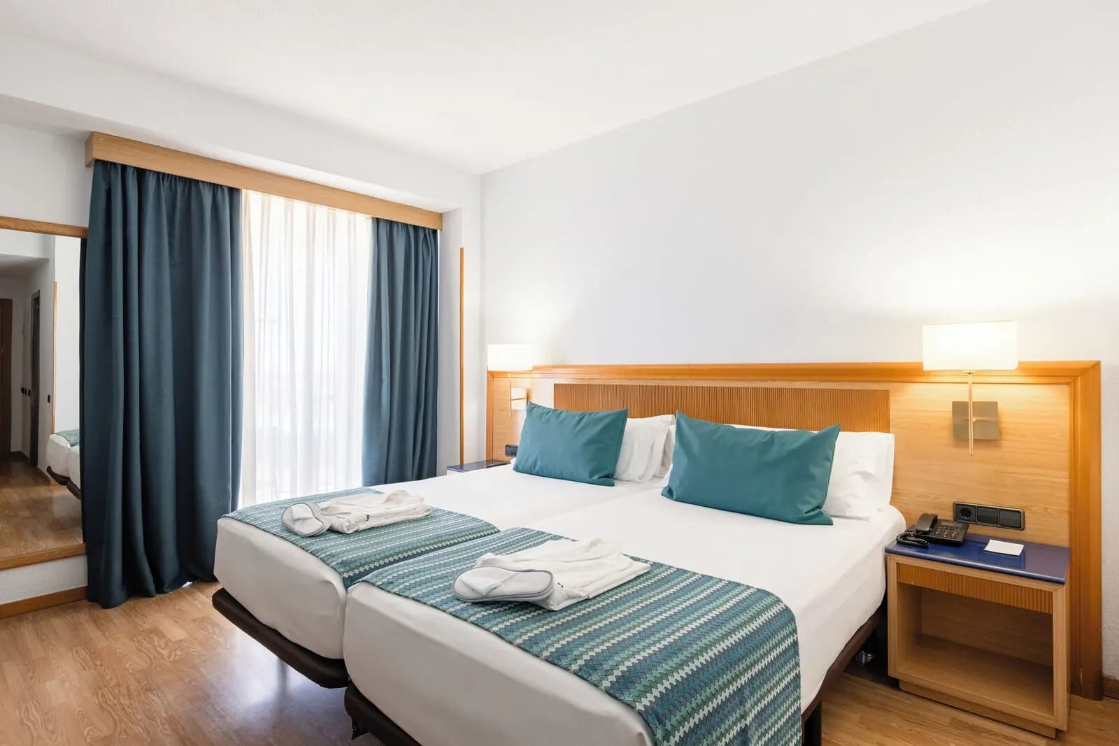 Catalonia Las Vegas: A hotel room with a double bed, a nightstand, a mirror, and a window with curtains